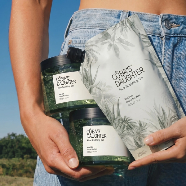 Endless Summer collection CoBa's Daughter Woman wearing jeans holding CoBa's Daughter aloe gel jars and a refill pouch under the sun