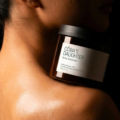Jar of CoBa's Daughter Coffee Body Scrub on a woman shoulder with glowing skin