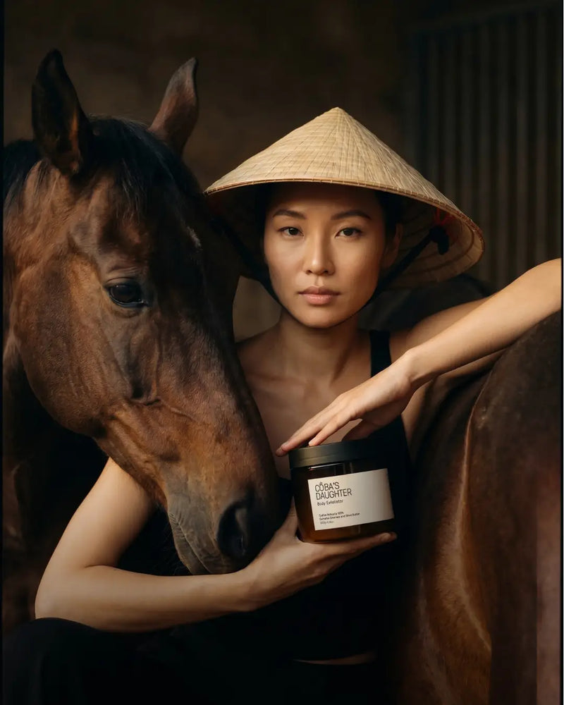 Woman in traditional Nón Lá holding a jar of CoBa's Daughter in equestrian barn