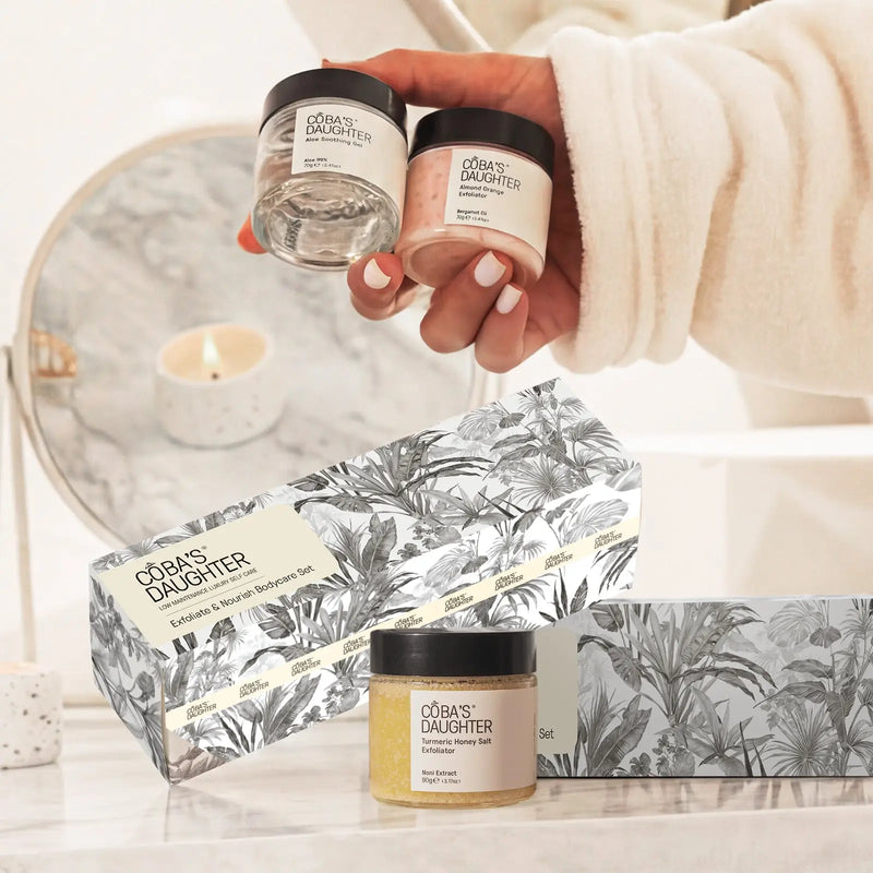 CoBa's Daughter 3-Piece Exfoliate and Nourish Gift Set with hands holding Aloe Soothing Gel and Almond Orange Exfoliator jars