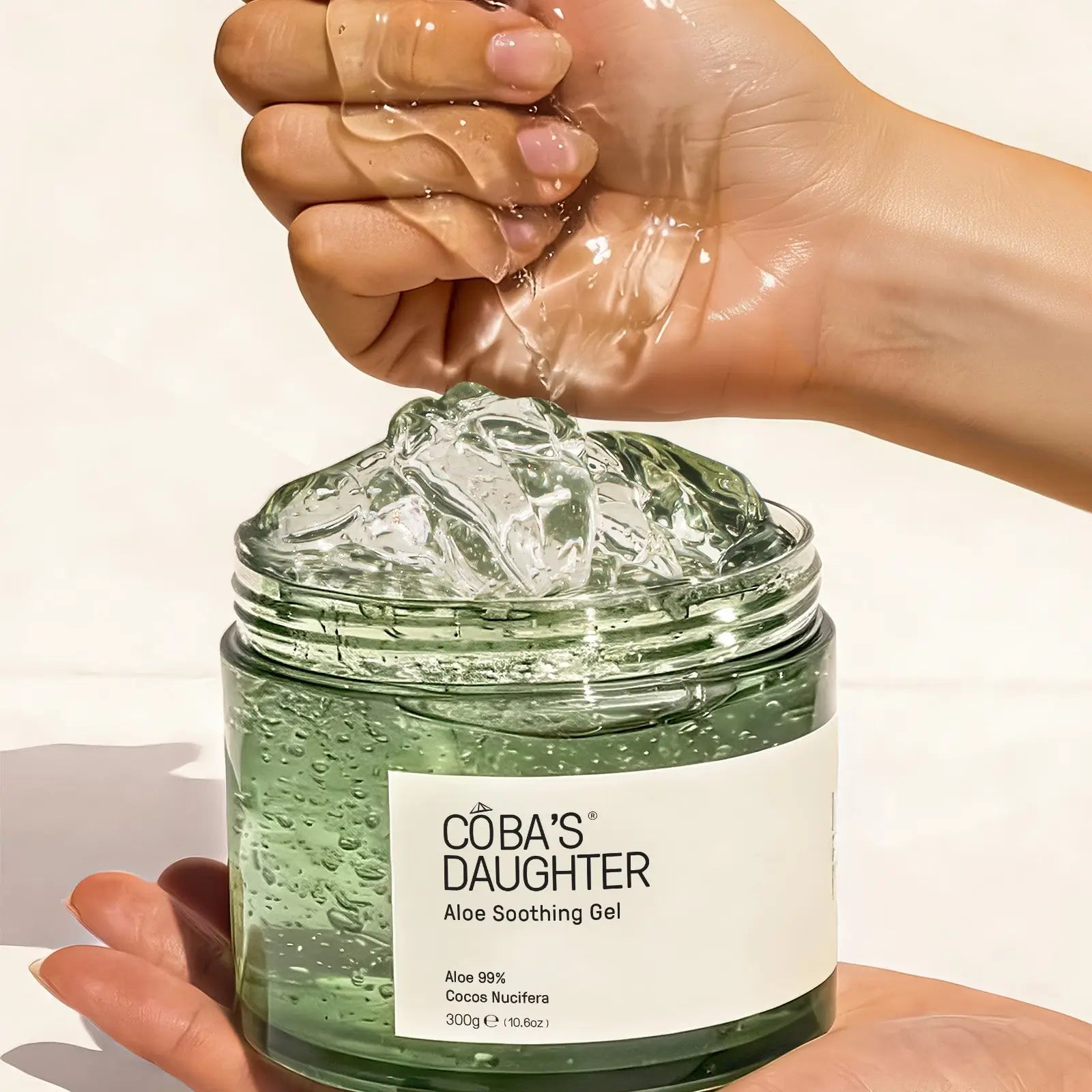 Hands scooping CoBa's Daughter 99% Pure Aloe Soothing Gel showing clear translucent texture for hydration