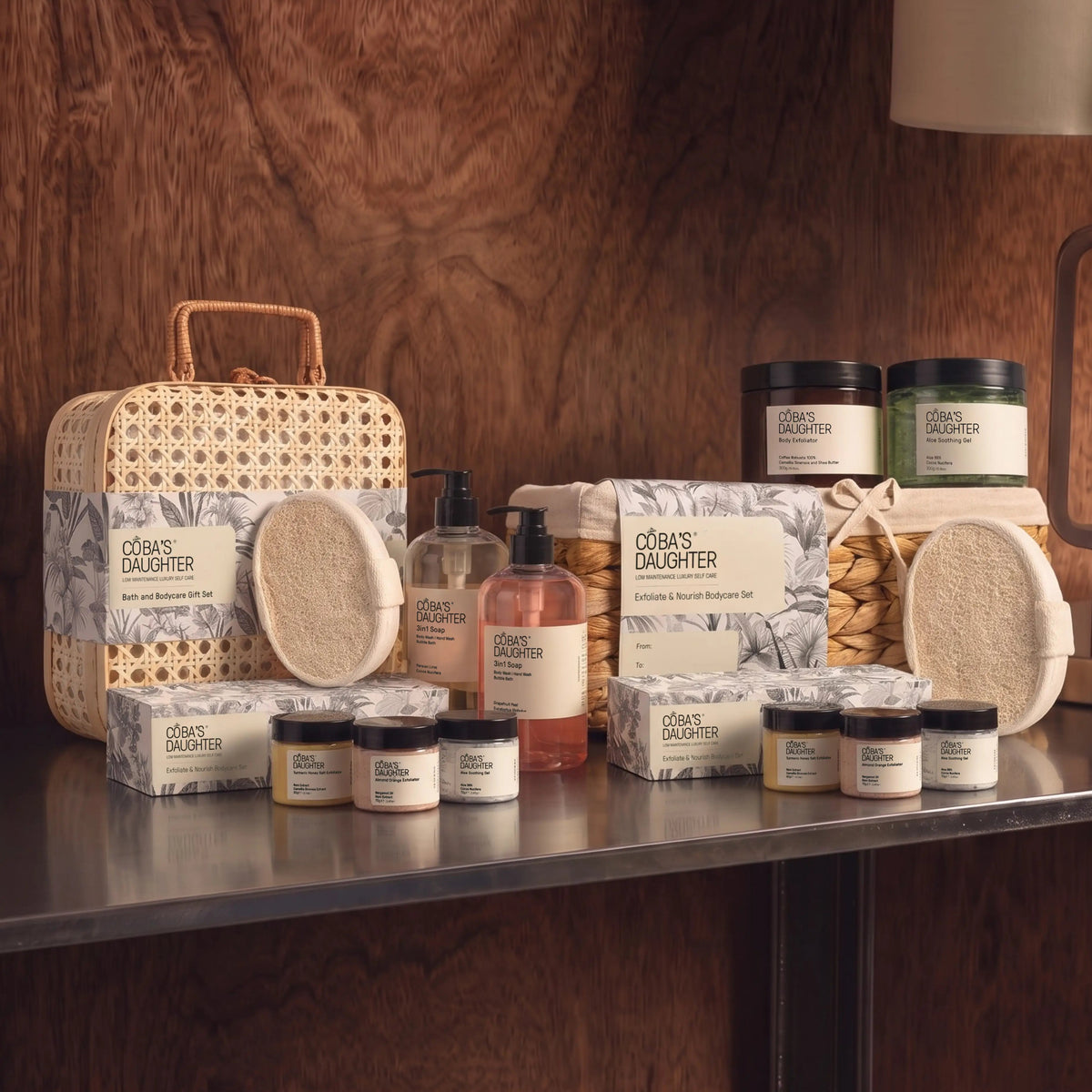 CoBa’s Daughter The Grand Gesture bath and body gift sets displayed in a rattan case and woven basket on a shelf.
