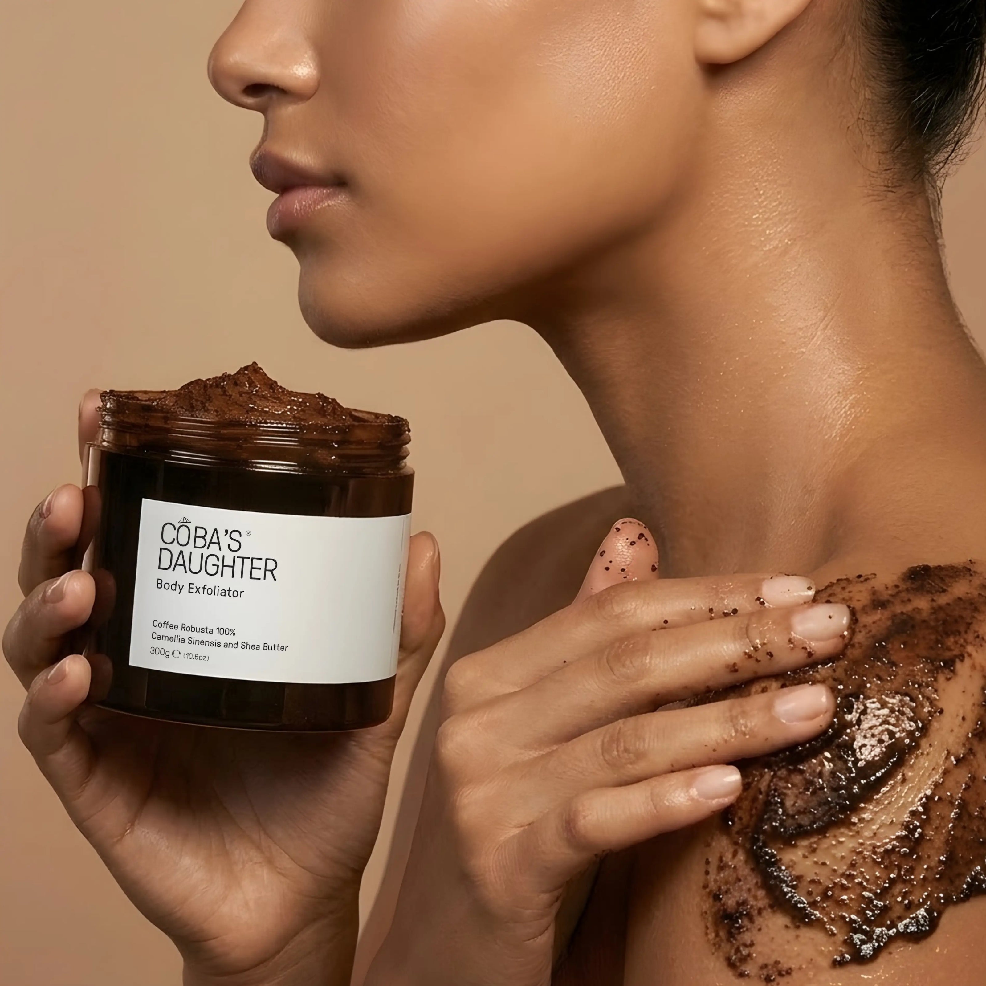 A woman applying a CoBa's Daughter Coffee Body Scrub onto the shoulder in a spa-like atmosphere